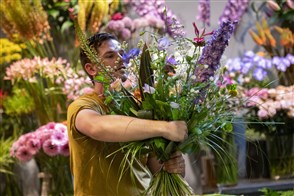 Een man in een bloemenzaak stelt een boeket samen