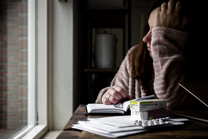 Een vrouw in ochtendjas met gesloten laptop, brieven van het UWV en antidepressiva medicijnen.