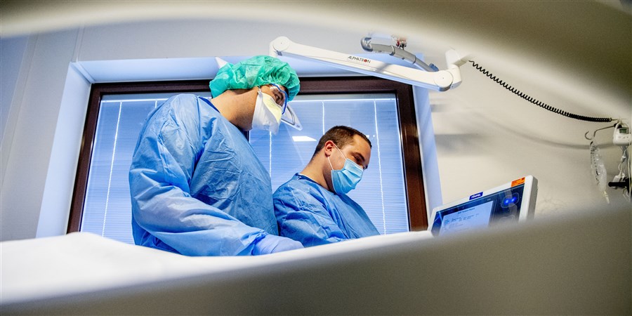 Een arts en een verpleegkundige met mondkapjes aan het werk op de intensive care