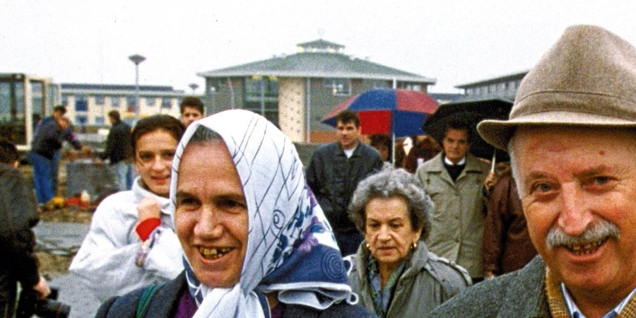 Een groep van zeventien oudere Bosnische vluchtelingen loopt woensdag door de regen over het terrein waar zij eerdaags gehuisvest zal worden.>>