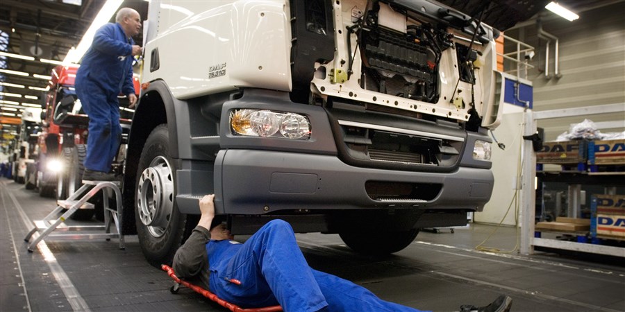 Werknemers leggen laatste hand aan vrachtwagen in fabriek