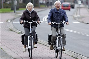 Bejaard echtpaar fietst op fietspad
