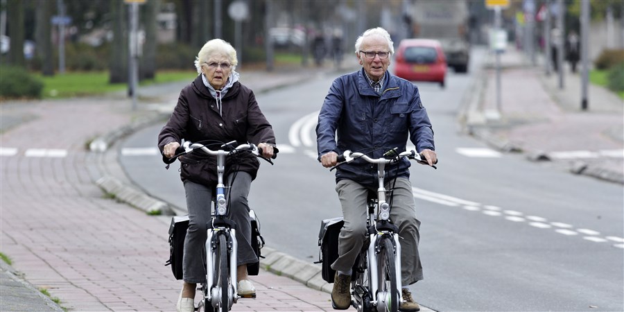 Bejaard echtpaar fietst op fietspad