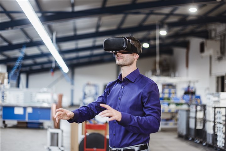 Company employee wearing VR goggles in shop floor