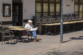 Oudere man zit de krant te lezen op een leeg terras