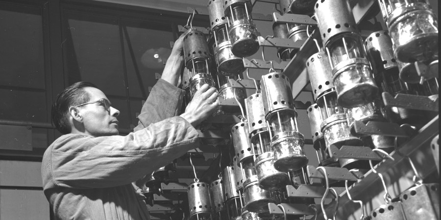 Bedieningsman neemt een benzinelamp uit een uitgifterek in de Staatsmijn Emma. 1951 Bedieningsman neemt een benzinelamp uit een uitgifterek in de Staatsmijn Emma. 1951