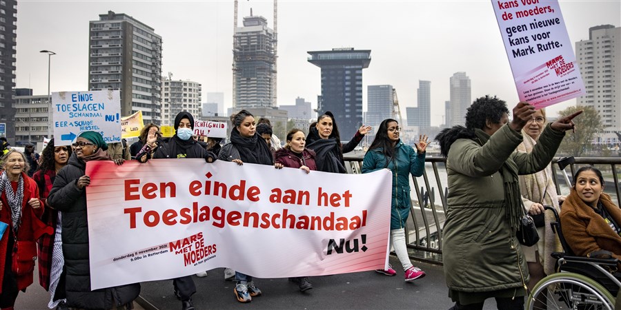 People protesting with banners against Dutch childcare benefits scandal
