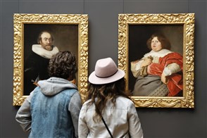 2 bezoekers kijken naar schilderijen met daarop dikke mensen