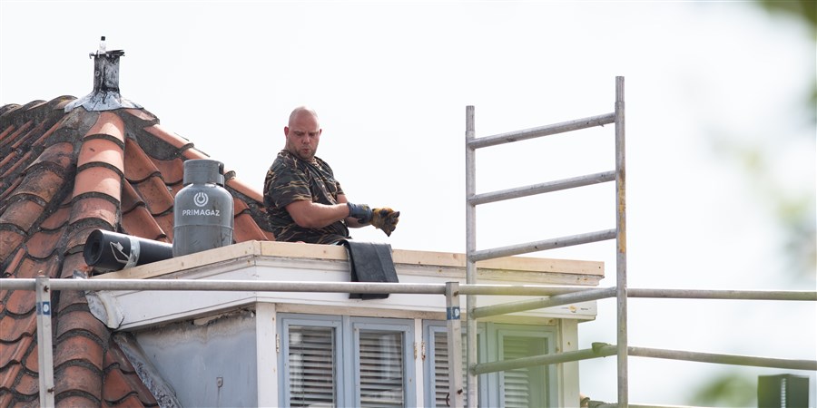 plaatje man boven op een dakkapel aan het werk.