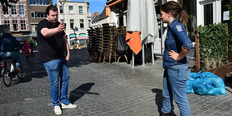 Een man en een vrouw bespreken de inrichting van een terras volgens de coronavoorschriften