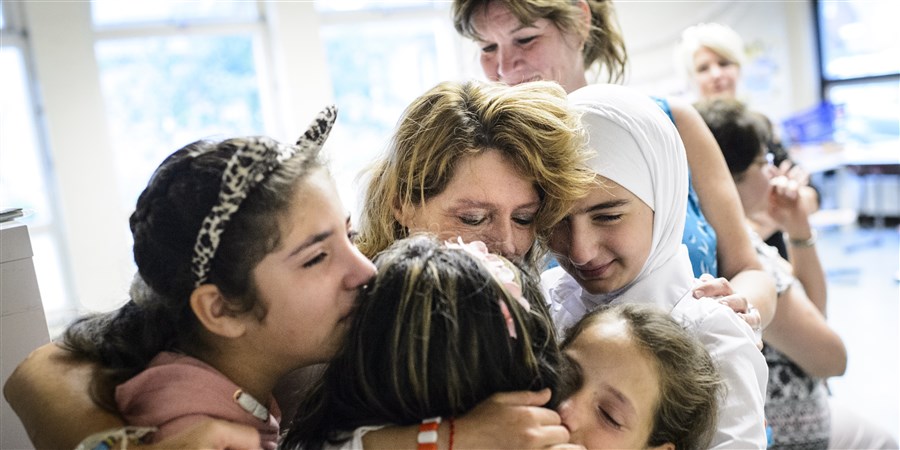 Children from an asylum shelter saying goodbye to their teacher at the end of the school year.