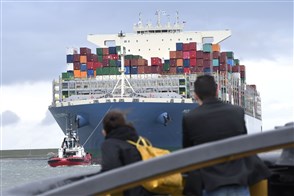 Mensen kijken naar enorm containerschip dat in de rotterdamse haven binnen komt