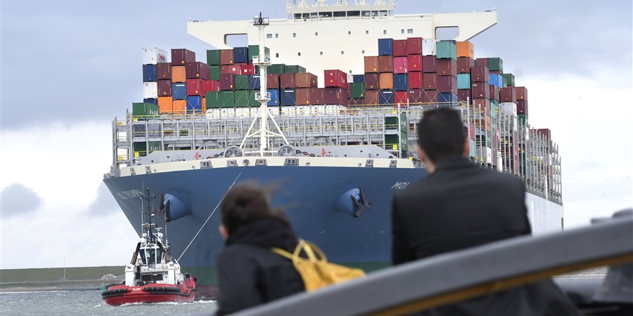 Mensen kijken naar enorm containerschip dat in de rotterdamse haven binnen komt