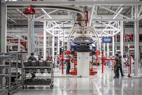 Autofabriek van Tesla in Tilburg waar mensen werken aan auto&#x27;s die aan de band hangen