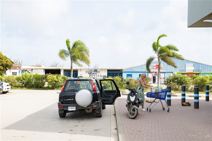 Mevrouw laadt boodschappen in op Bonaire in auto