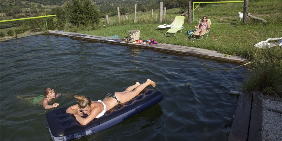 Kinderen vermaken zich in het privé natuurzwembad, wat gevuld is met water uit de bron.