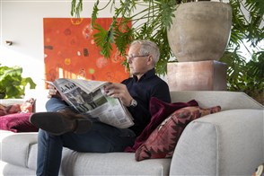 Man in huiskamer leest de krant op de bank