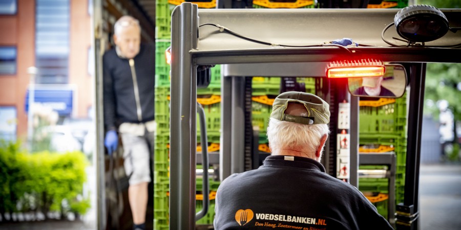 Vrijwilligers van de voedselbank in den haag zijn voedselpakketten aan het inladen.