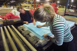 Arbeidskrachten verwerken schuimrubber tot een matras in een schuimrubberfabriek.