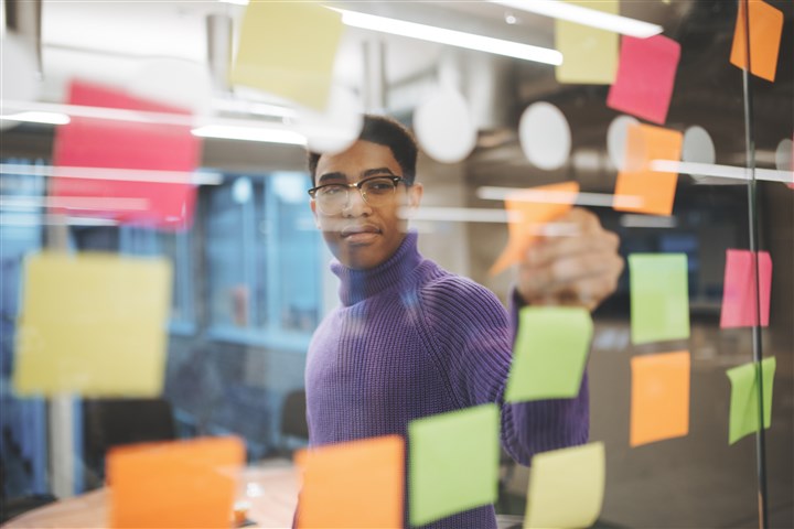 Man removes coloured memo note from window