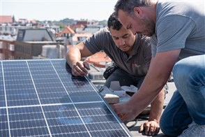 Twee mannen monteren een zonnepaneel op een dak