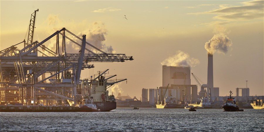 Containerhaven met schepen en electriciteitscentrale op de achtergrond