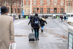 Een toerist die met zijn koffer naar Amsterdam Centraal loopt