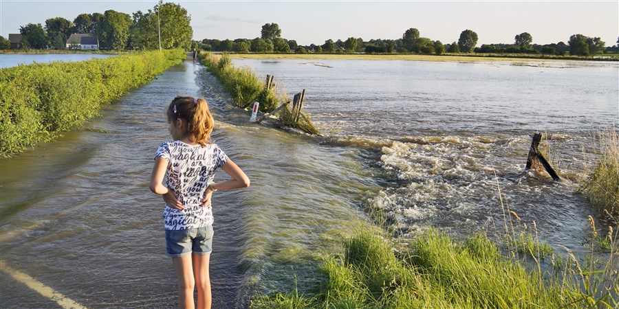 Meisje staat bij overstroomde uiterwaarden in Limburg