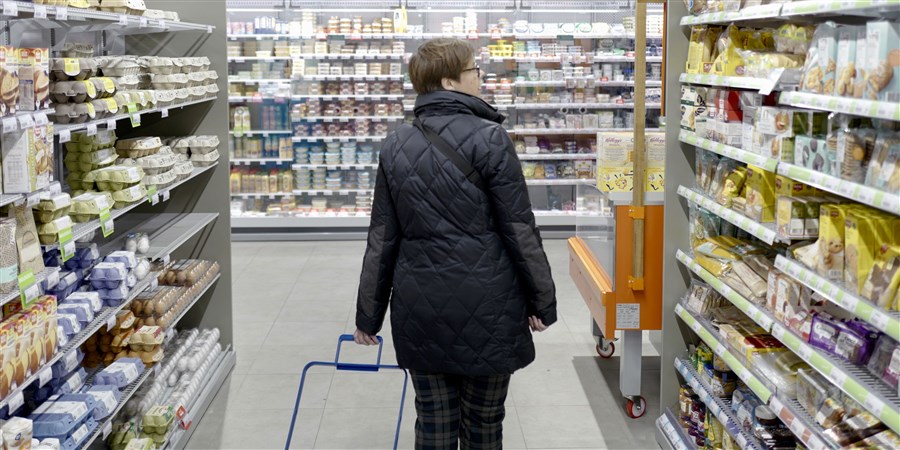 Vrouw doet boodschappen in een supermarkt met een boodschappenkar