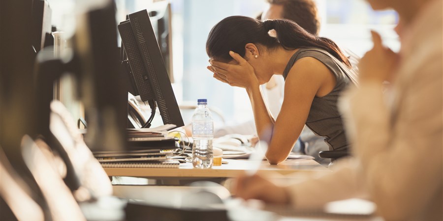 Stressed businesswoman with head in hands at office desk