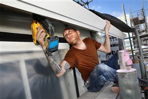 Een bouwvakker brengt isolatie aan bij het dak van een woning