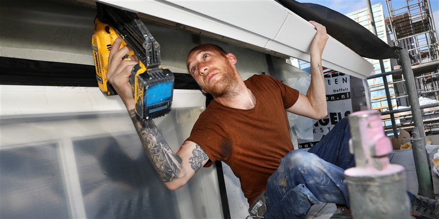 Een bouwvakker brengt isolatie aan bij het dak van een woning