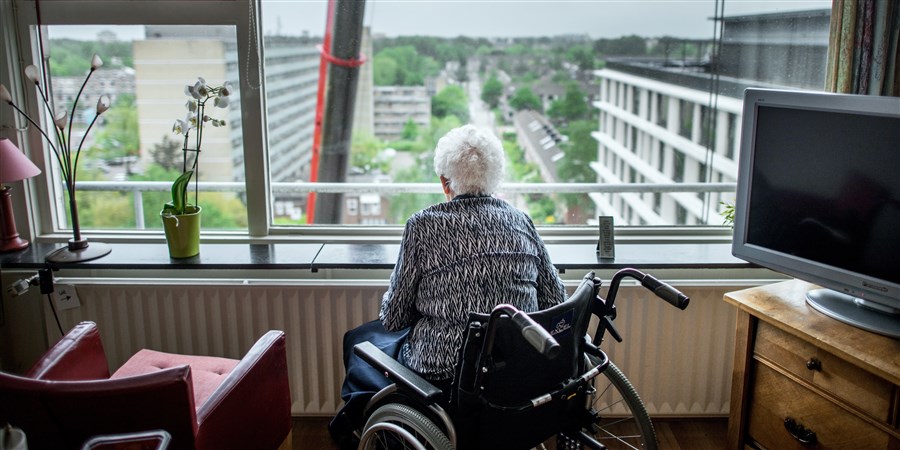 Oudere dame in rolstoel kijkt naar buiten