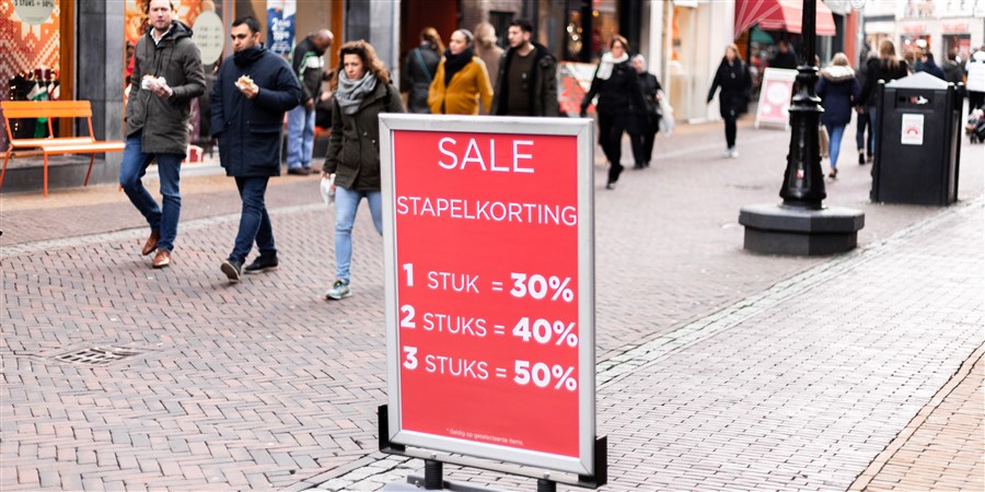 een drukke winkelstraat in Utrecht, reclamebord biedt kortingen aan, het is sale