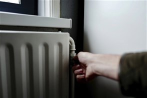Hand draait aan de radiatorknop van de centrale verwarming in huis