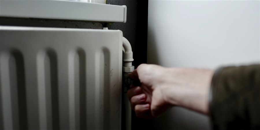 Hand draait aan de radiatorknop van de centrale verwarming in huis
