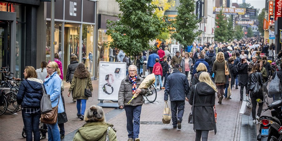 Winkelend publiek, man met een bos bloemen in een winkelstraat in Apeldoorn