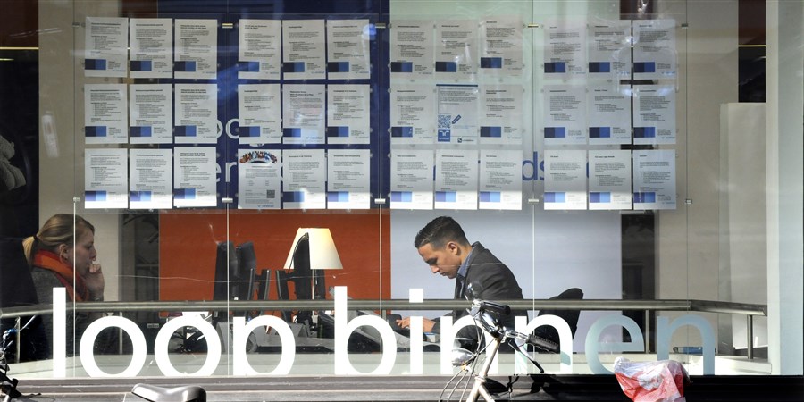 Etalage van een uitzendbureau, waar twee medewerkers aan het werk zijn