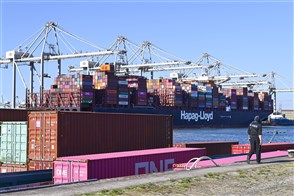 Containerschip aan kade met rij containerkranen