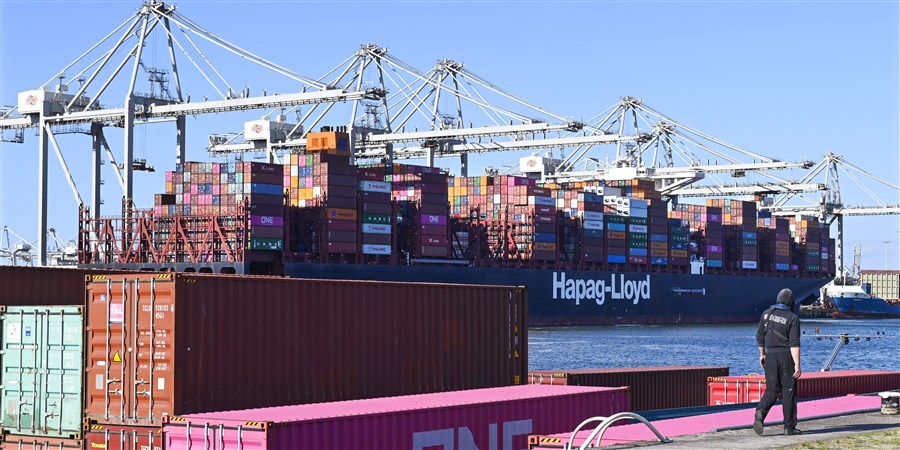 Containerschip aan kade met rij containerkranen