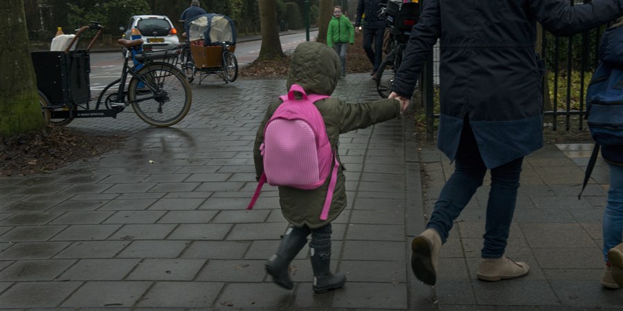 kinderen lopend op straat aan de hand van de moeder