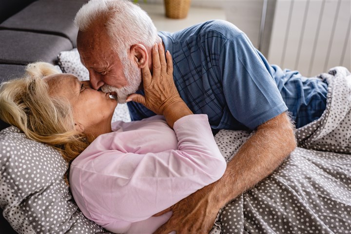 An elderly couple cuddling in bed.