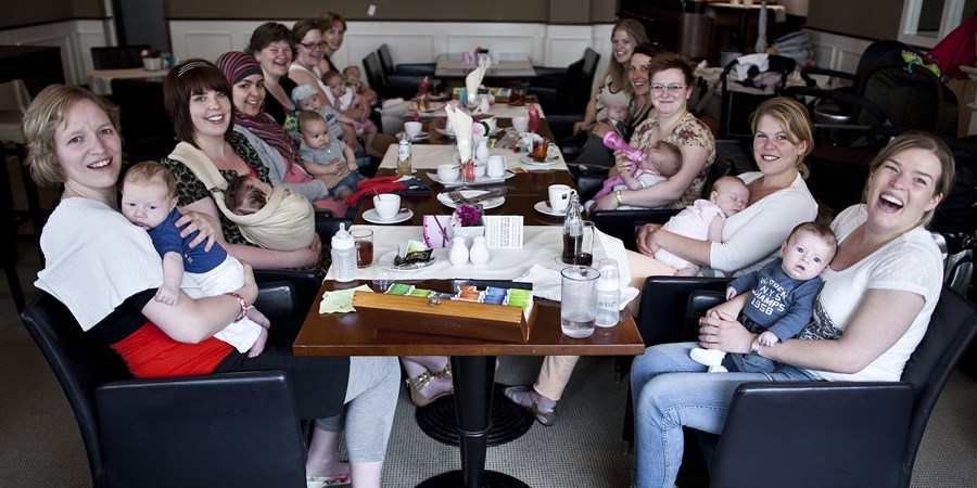 Groep moeders met kinderen aan tafel