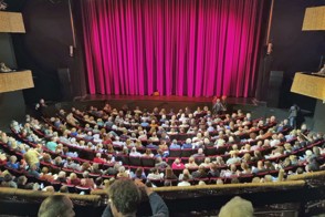 Volle zaal met gesloten gordijn in stadsschouwburg