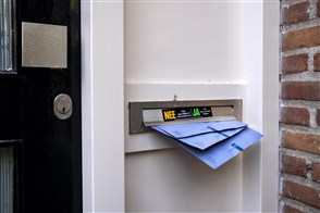De blauwe envelop van de belastingdienst steekt uit brievenbus
