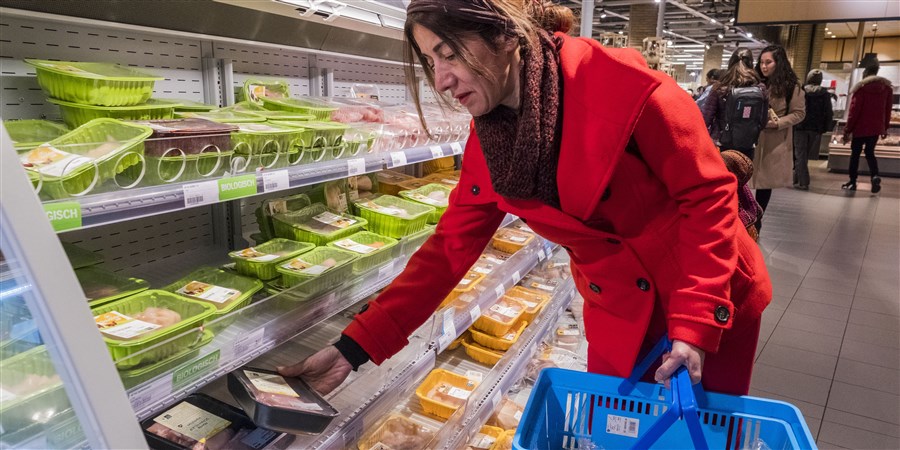 Een vrouw koopt groente, vlees en kaas bij de supermarkt