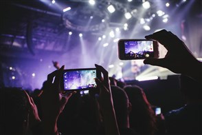 iemand maakt een foto van een concert op zijn mobiele telefoon.