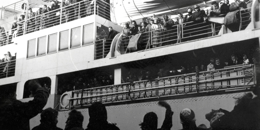 Nederland, plaats onbekend, begin 1956. Emigratie vanuit Nederland. Achterblijvers op de kade zwaaien als afscheid van de vertrekkende familie. | Nationaal Archief