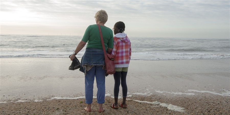 Moeder met haar geadopteerde dochter op het strand