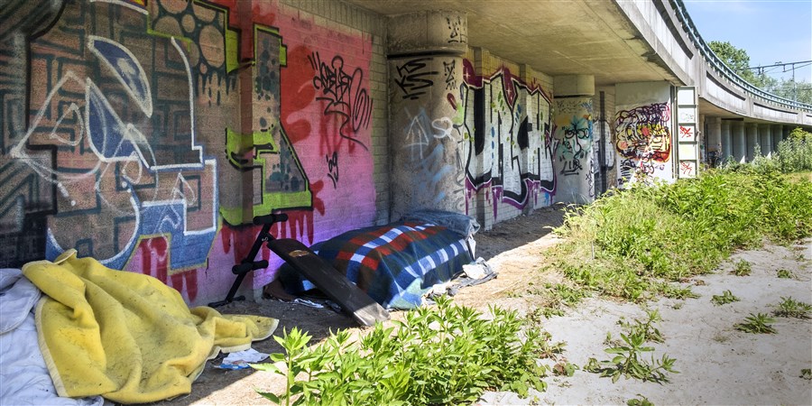 Keurig opgemaakt bed van een dakloos persoon onder spoorviaduct in Rotterdam Delfshaven